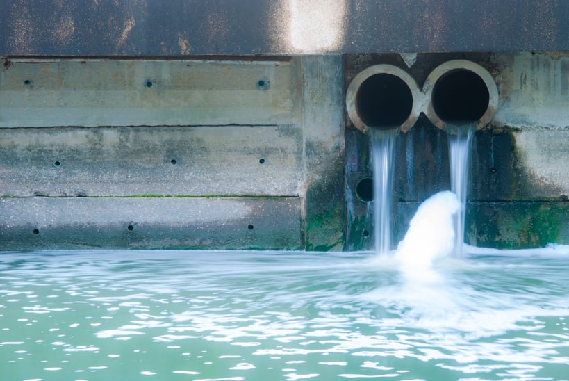 Image of waste water pouring out of two pipes into a larger body of waste water.